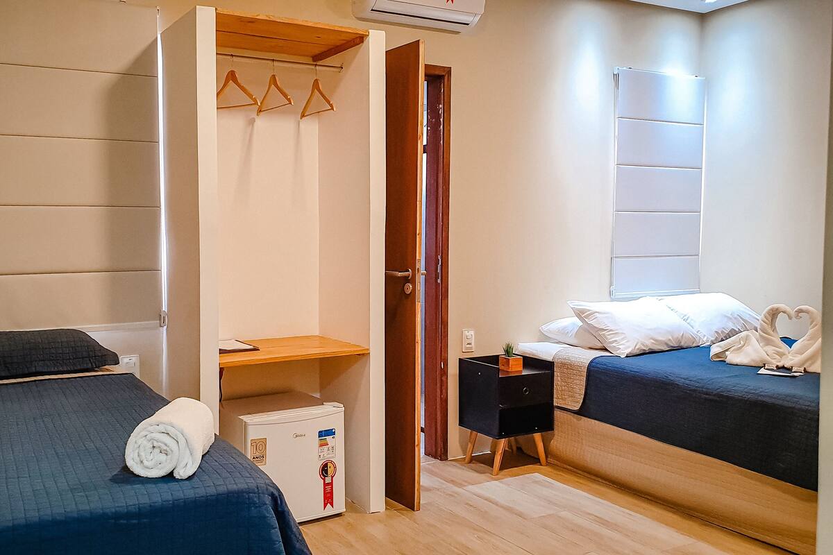 Une chambre d’hôtel avec deux lits, un petit bureau, une armoire et un mini-réfrigérateur.