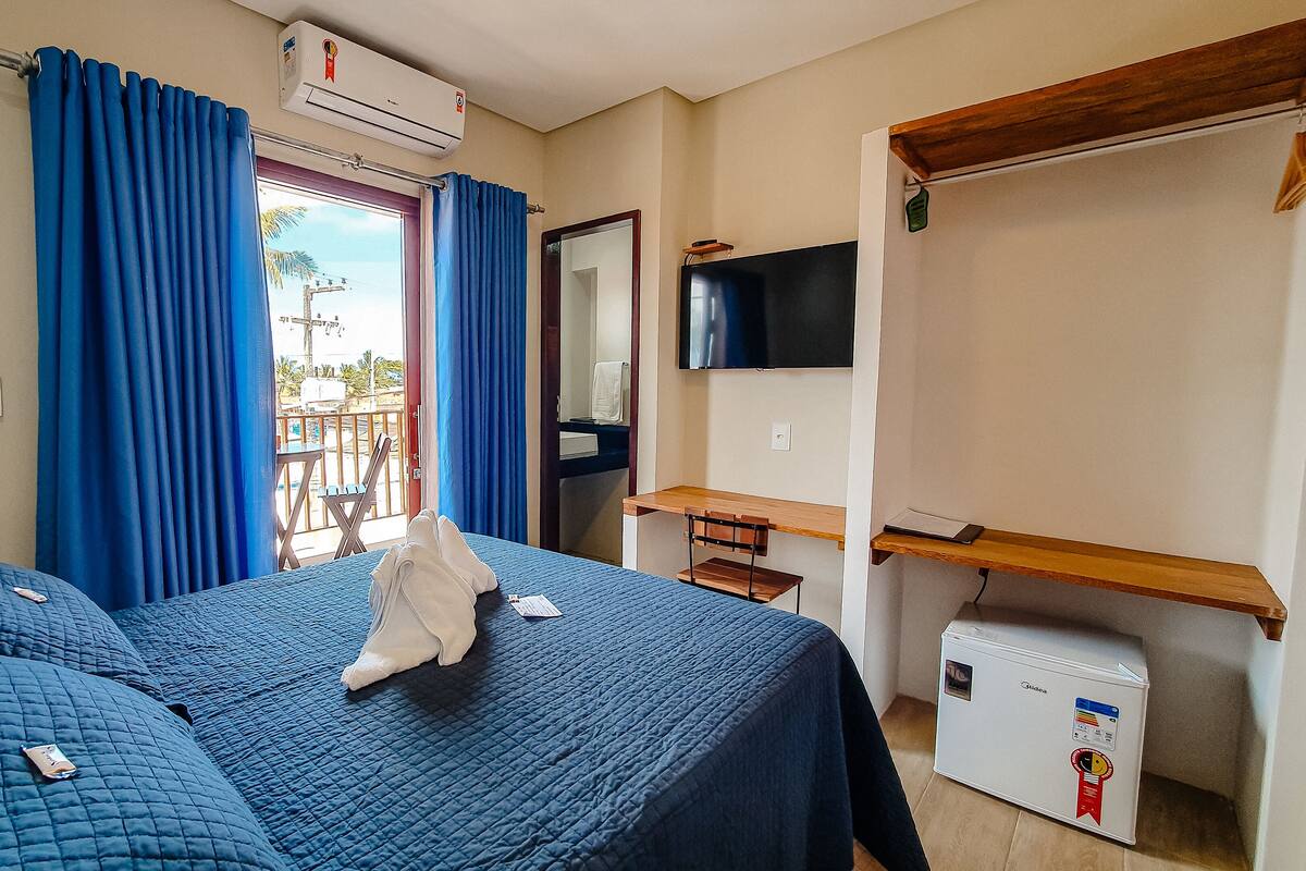 Une chambre d’hôtel avec deux lits, un bureau, une télévision et un petit réfrigérateur.