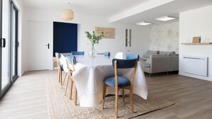 A modern dining area with a round table, chairs, and a vase of flowers. - MA RÉ HOTES        . (Le Bois-Plage-en-Ré)