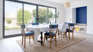 A dining area with a large table, chairs, and a view through large windows. - MA RÉ HOTES        . (Le Bois-Plage-en-Ré)