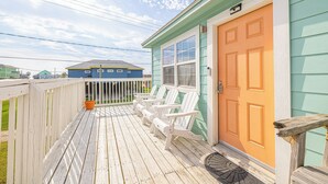 A wooden deck with white Adirondack chairs, a wooden fence, and a bright orange door. - Pet Friendly - Walk to the Beach, Cozy Home (Freeport)