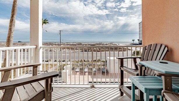 Un balcón con vista a la playa y al océano, con una mesa y sillas.