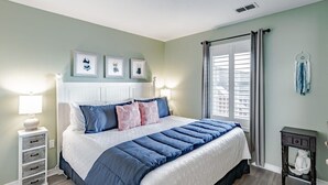 Un dormitorio con una cama grande, una mesita de noche, un aparador y una ventana con cortinas.