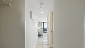 En smal, väl upplyst hall med ett klinkergolv som leder till ett rum med en balkong.