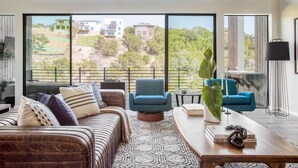 Ein geräumiges Wohnzimmer mit großem Fenster, einem Sofa, einem Couchtisch und einem blauen Sessel.