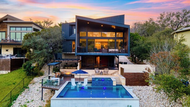 Ein modernes, zweigeschossiges Haus mit Swimmingpool, Sitzgelegenheit im Freien und einem großen Panoramafenster.