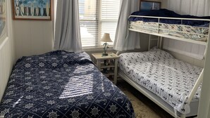 A bedroom with bunk beds, a small bedside table, a lamp, and a painting of surfboards. - 1st floor condo mid town just a short walk to many fun things to do! (Ocean City)