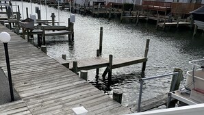 A wooden dock leading to a marina with boats, connected to a row of residential buildings. - 1st floor condo mid town just a short walk to many fun things to do! (Ocean City)