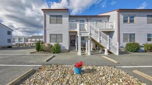 A two-story building with a white exterior, a central entrance, and a staircase leading to the upper floor. - 1st floor condo mid town just a short walk to many fun things to do! (Ocean City)