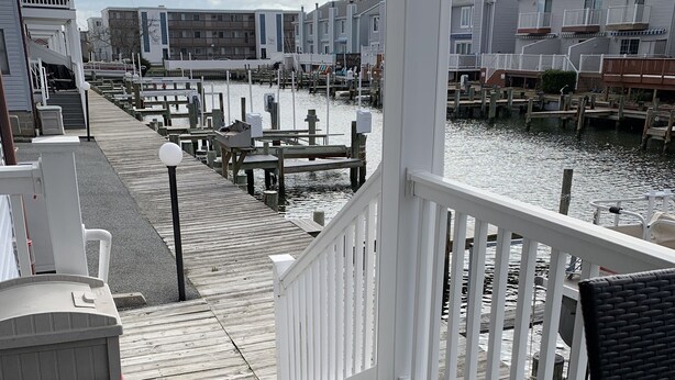 A wooden deck with a white railing, leading to a marina with boats docked. - 1st floor condo mid town just a short walk to many fun things to do! (Ocean City)