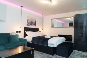 A modern hotel room with a large bed, a sofa, a desk, and a mirror. - Willow Studio (Leeds)
