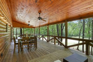 Une terrasse en bois avec une table et des chaises, entourée de grandes fenêtres donnant sur une for êt.