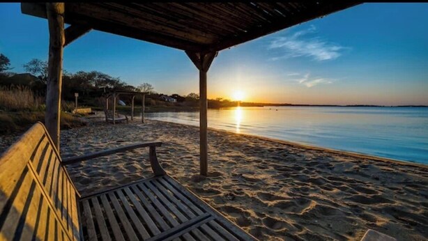 Un banco de madera bajo un refugio en la playa al atardecer.