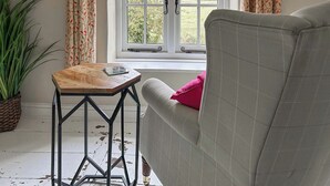 Une pièce avec un canapé, une petite table en bois, une plante en pot et une fenêtre avec des rideaux.