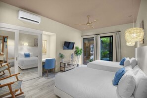 Et hotelværelse med to senge, et skrivebord, en stol, en aircondition og både en ventilator og et fjernsyn.