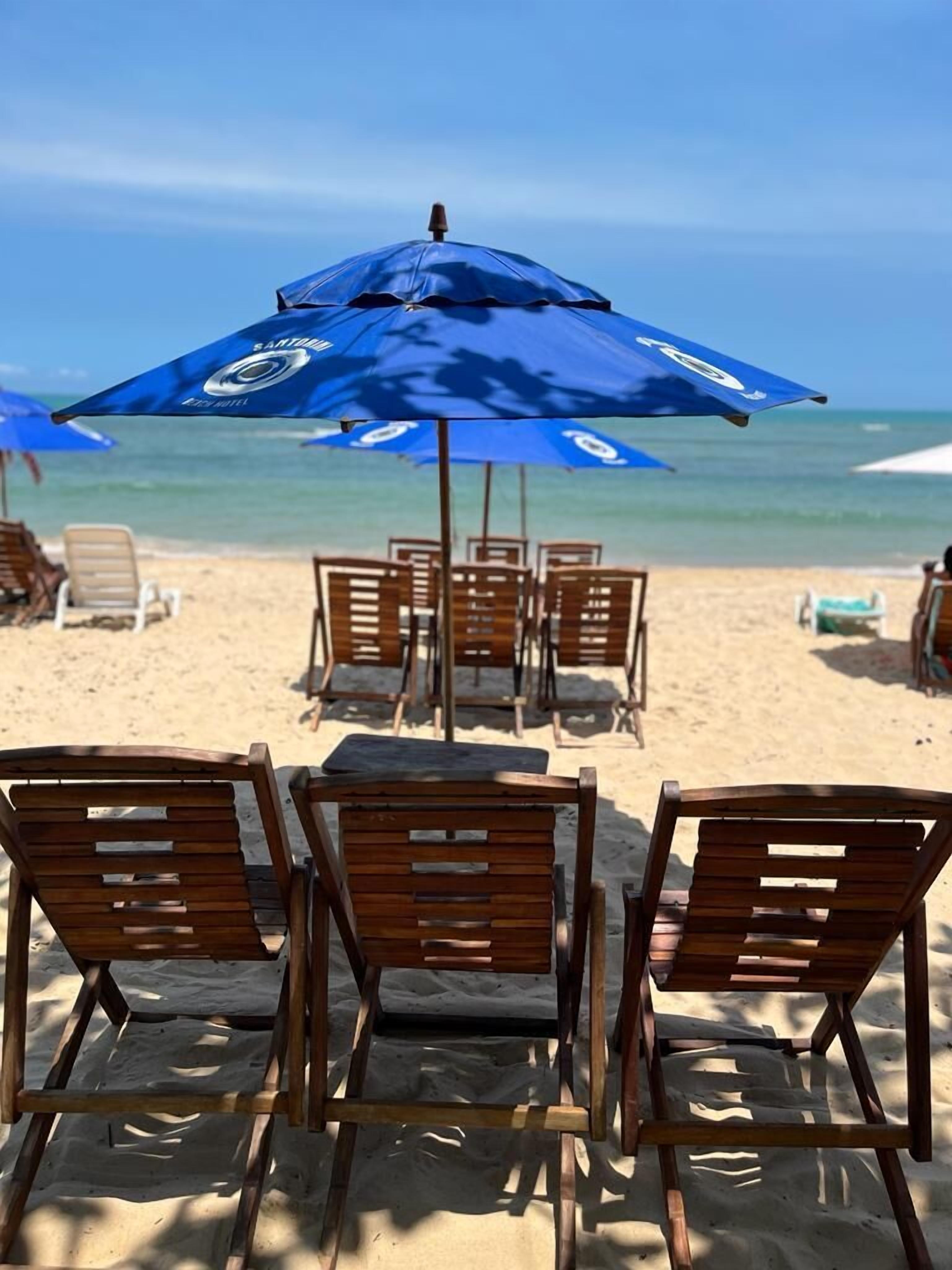 Na praia, areia branca, barracas de praia de cortesia, espreguiçadeiras 