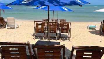 Na praia, areia branca, barracas de praia de cortesia, espreguiçadeiras