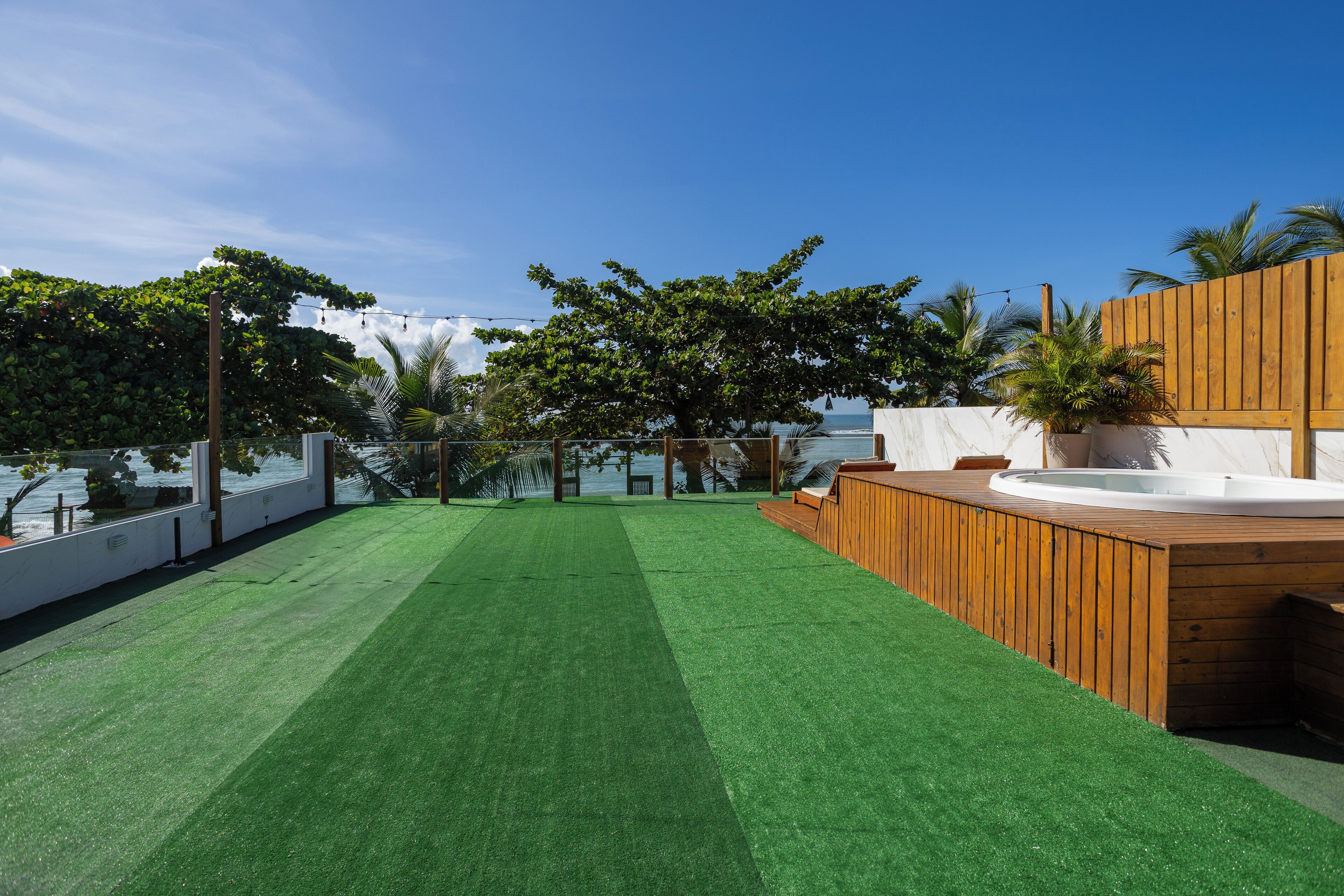 A rooftop with artificial grass, a wooden deck, and a hot tub.