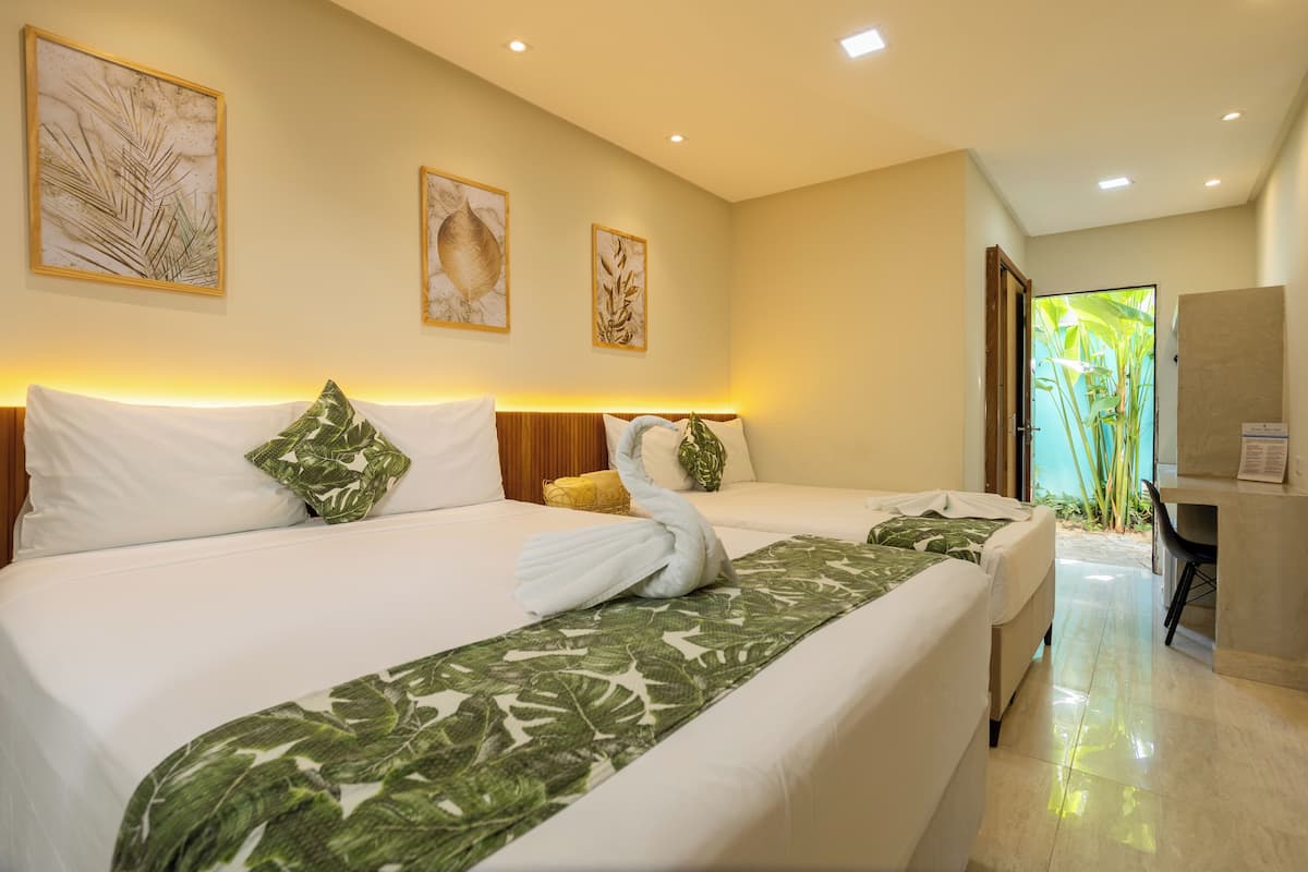 Une chambre d’hôtel avec deux lits, un bureau et une vue sur la verdure environnante.