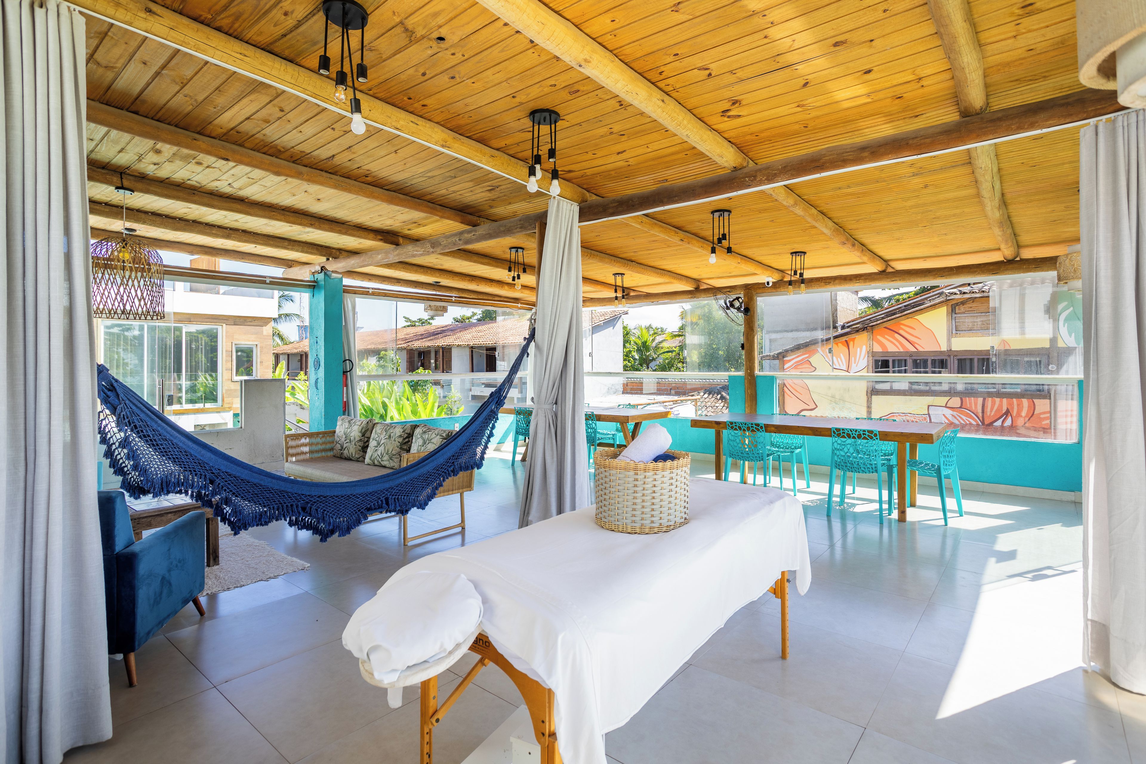 Quarto amplo com rede, mesa com toalha branca e vista para o exterior.