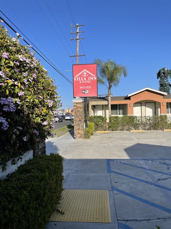 A Villa Inn & Suites sign with a brick pillar, surrounded by greenery and a clear sky. - Villa Inn & Suites (Inglewood)