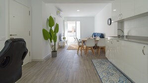 Un appartement moderne comprenant un coin repas, une cuisine et une grande plante en pot.