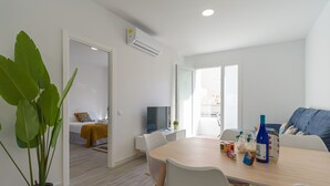 Un salon moderne comprenant un coin repas, un téléviseur et une grande plante en pot.