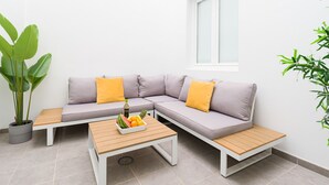 A modern outdoor seating area with a grey sofa, yellow cushions, and a wooden table with fruit. - Volcano La Colorada By CanariasGetaway (Las Palmas de Gran Canaria)