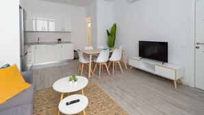 A modern apartment with a kitchen, dining area, and living room. It includes a sofa, a coffee table, a TV, and a large plant. - Volcano La Colorada By CanariasGetaway (Las Palmas de Gran Canaria)