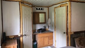 Un dormitorio con puerta de madera, techo blanco, armario de madera, un lavamanos y un espejo.