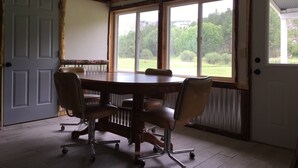 Un salón de conferencias con una gran mesa, cuatro sillas y vistas a un paisaje verde a través de amplias ventanas.