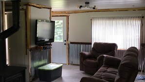 Una sala de estar con una televisión, un sofá, una silla y una chimenea.