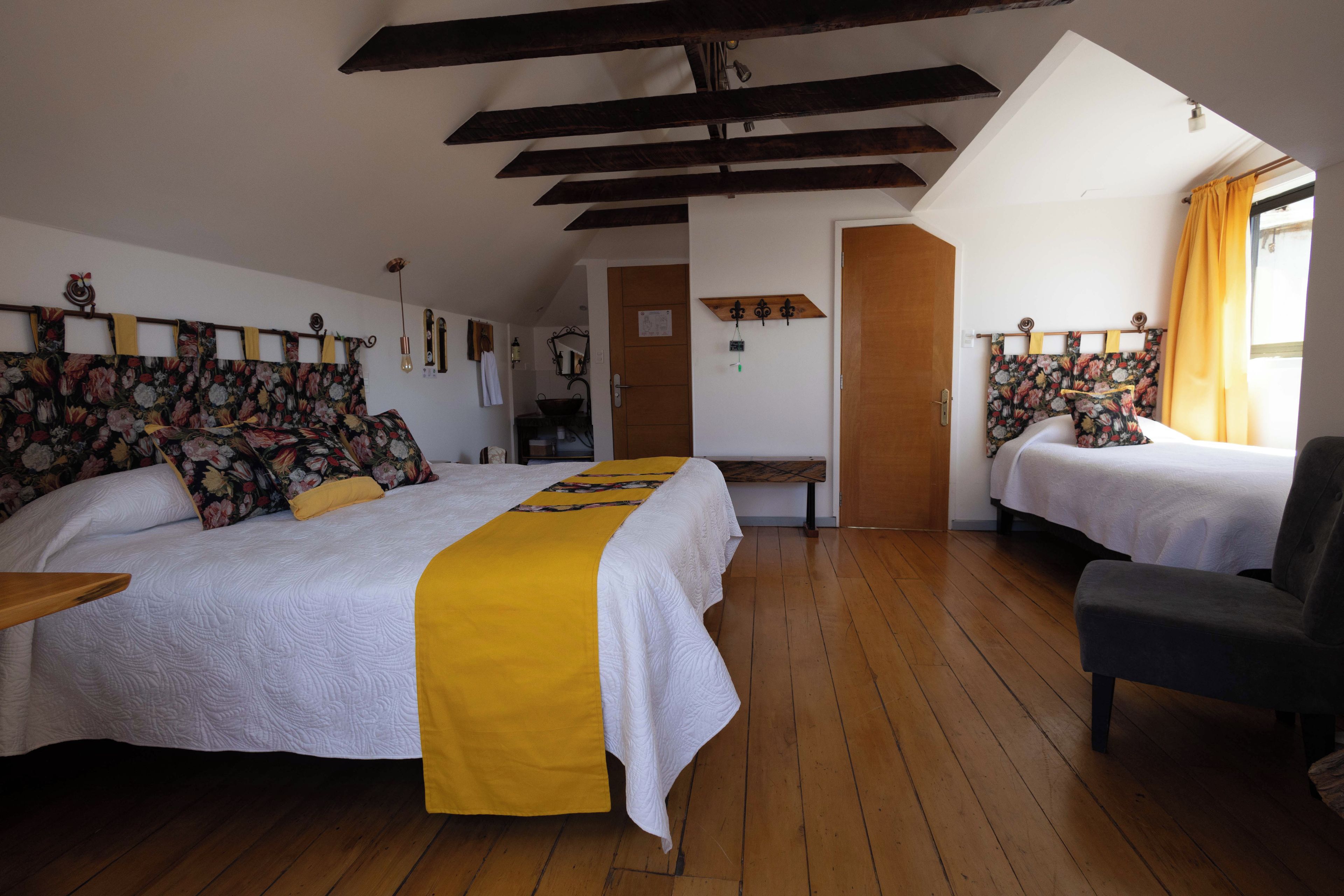 Una camera da letto con due letti, pavimento in legno, una panca e una sedia.
