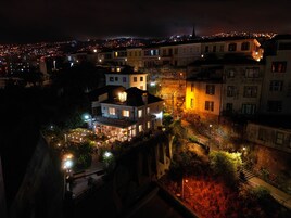 Vista nocturna de un pueblo histórico con edificios iluminados, una imponente aguja de iglesia y un patio bien iluminado.