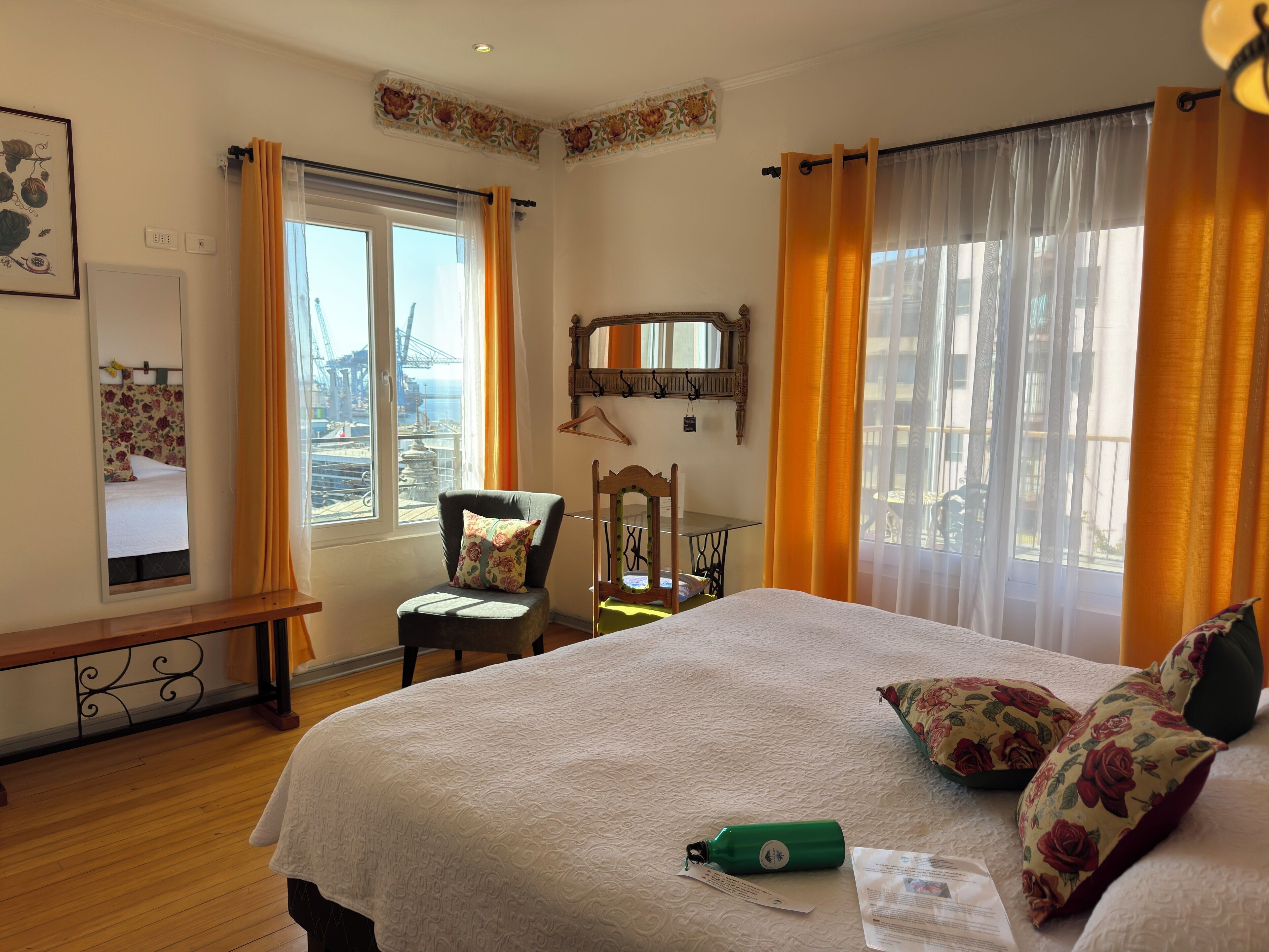 A bedroom with a bed, a chair, a table, and a window with curtains.