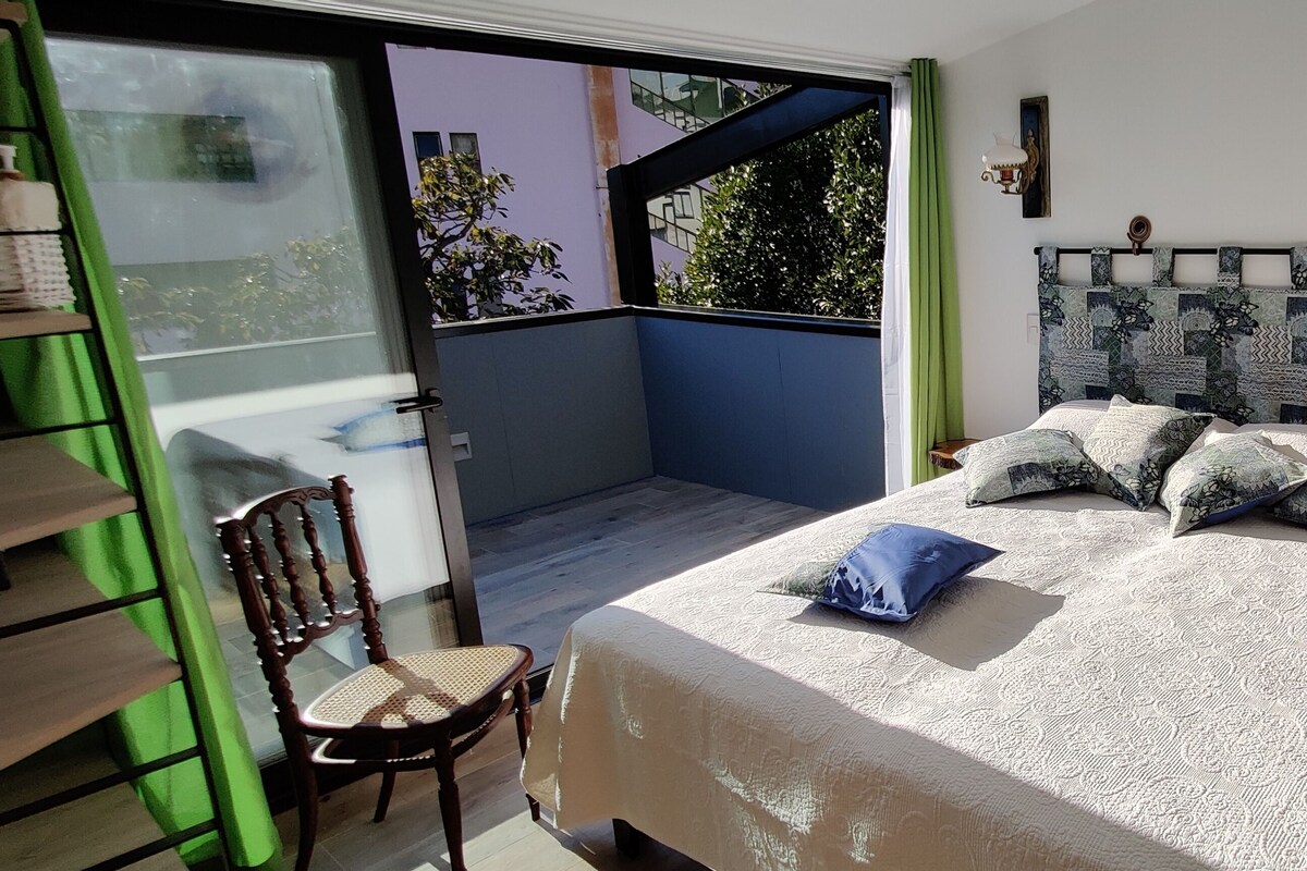 Een slaapkamer met een bed, een stoel, een nachtkastje en een raam.