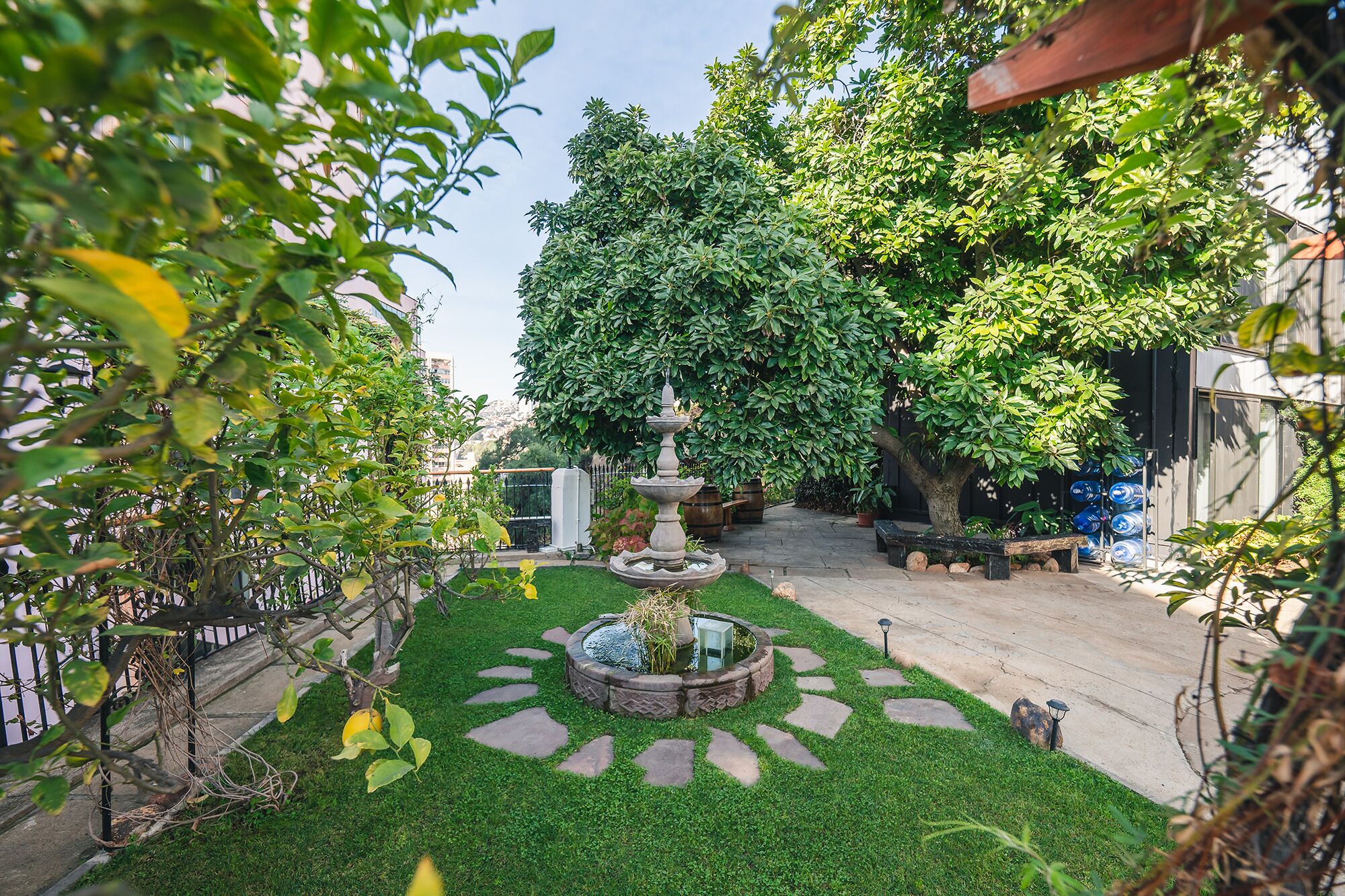 A garden with a central fountain, stone pathways, and lush greenery.