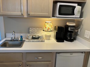 Une cuisine équipée d’un four à micro-ondes, d’une machine à café et d’un plateau avec des tasses et un vase.