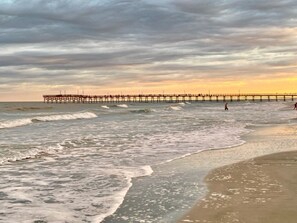 A pier extending into the sea with waves crashing against it.