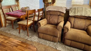 Un interior de caravana acogedor con una mesa de comedor de madera, sillas acolchadas y un sofá.
