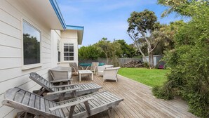 Um quintal com deck de madeira, móveis para área externa e piscina.