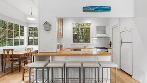 Uma cozinha moderna com ilha de madeira, banquetas, fogão e geladeira.