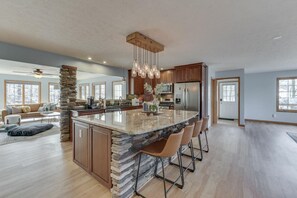 A spacious kitchen with a large island, modern appliances, and a stone accent wall. - 4 Paws Getaway (Columbus)