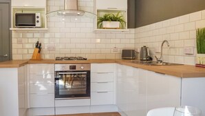 Een moderne keuken met witte kastjes, een ingebouwde magnetron, een gasfornuis en een roestvrijstalen oven.