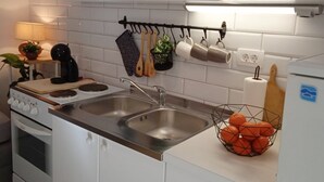 Ett modernt kök med vita skåp, rostfria vitvaror, en dubbel diskho och en bänkskiva med en fruktskål.