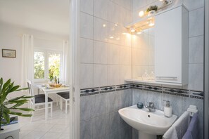 A modern bathroom with a sink, mirror, and tiled walls. - One bedroom apartment with terrace (Stari Grad)