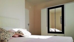 A bedroom with a bed, a wardrobe, and a mirror. - One bedroom apartment with seaview balcony (Nin)