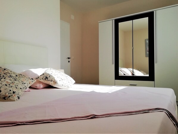 A bedroom with a bed, a wardrobe, and a mirror.