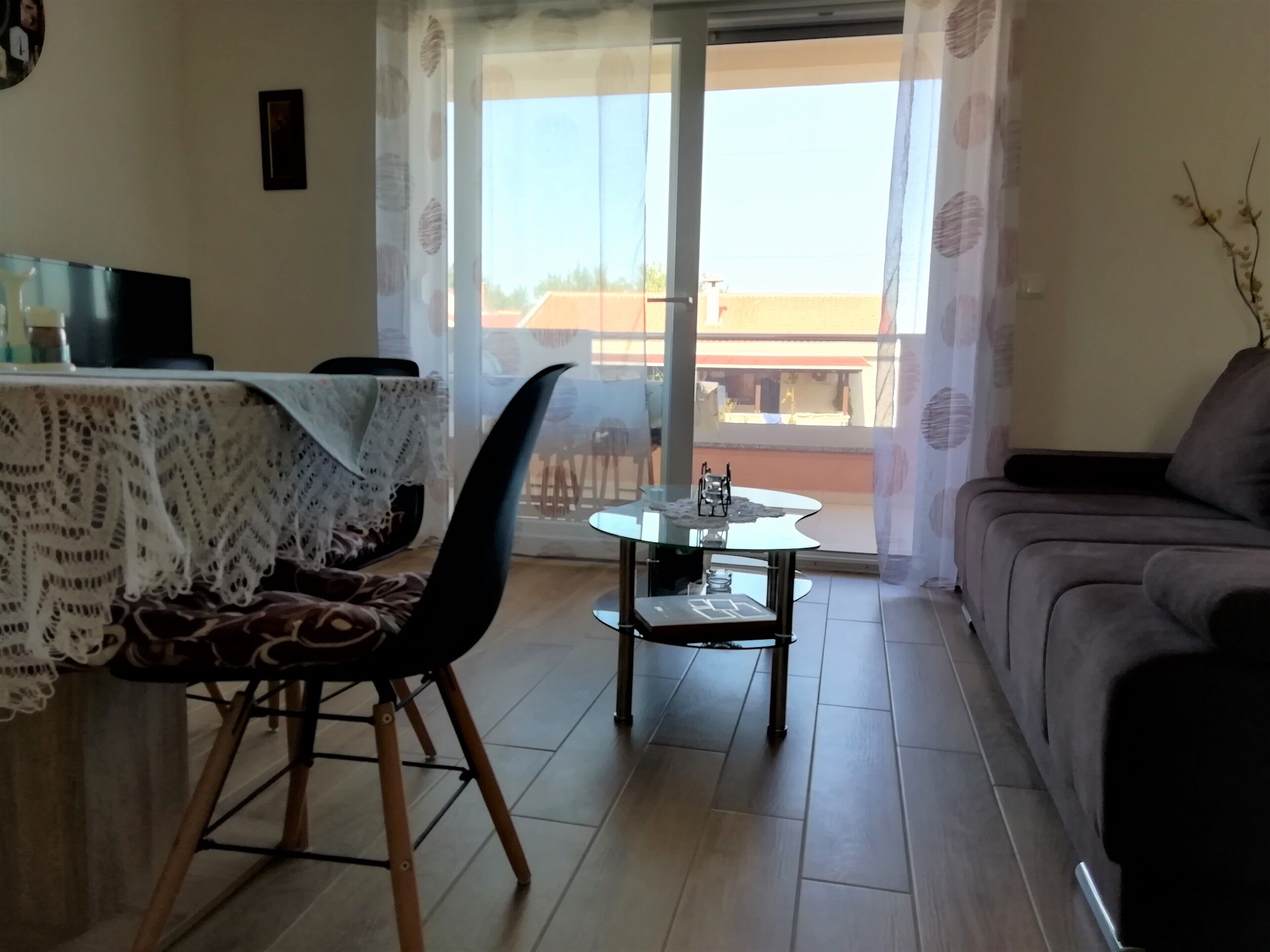 Ein Wohnzimmer mit einer Couch, einem Esstisch mit Stühlen und einem Couchtisch mit Glasplatte.