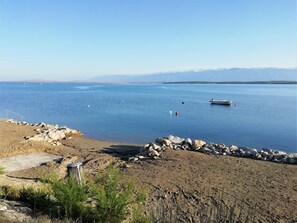 A beach with a rocky shoreline, a boat, and a clear view of distant mountains.